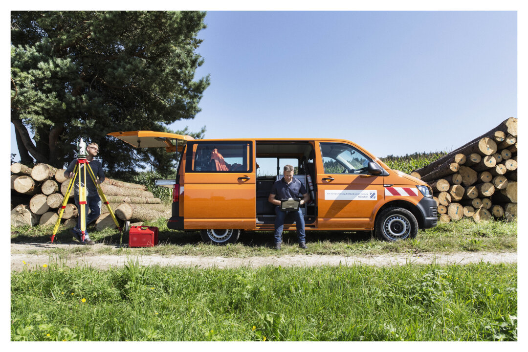 zwei Mitarbeiter des Vermessungsamts beim Arbeiten an einem Feldweg
